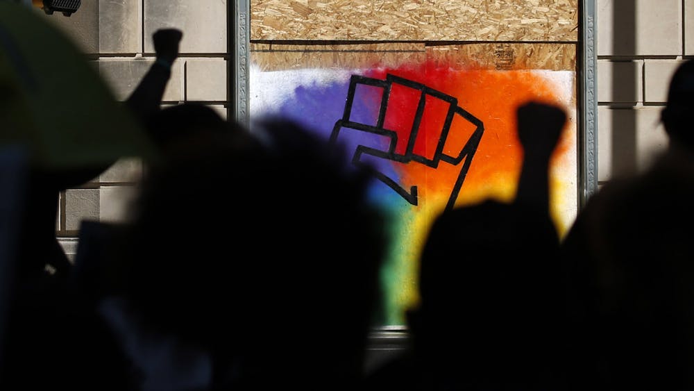 Protesters hold up a fist as they pass by a  painting of a fist during the Lead the Change: Juneteenth Rally on June 20, 2020, in Dallas.