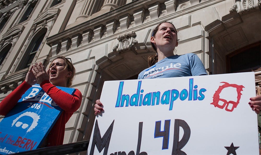 Campaign organizers Rachel Brada, left, and Elizabeth Hyde talk to a crowd of Bernie Sanders supporters about registering to vote after marching around the Indiana State Capital building during a rally Saturday afternoon.