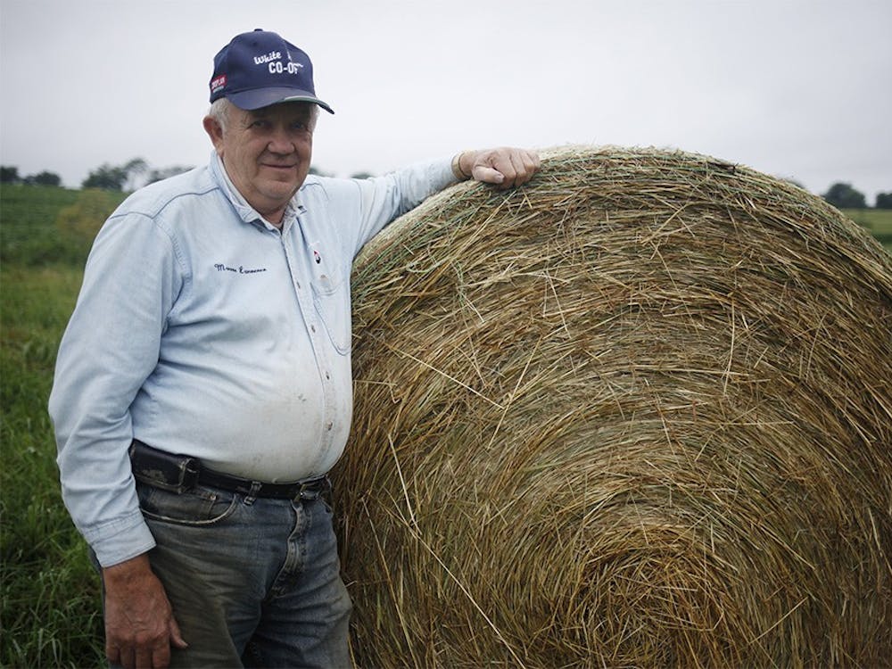 Joe Peden poses in front of a bale of hay on his property July 8, 2015, at Peden Farm in Bloomington. Peden is one of many farmers struggling to produce crops this year due to excessive rainfall.