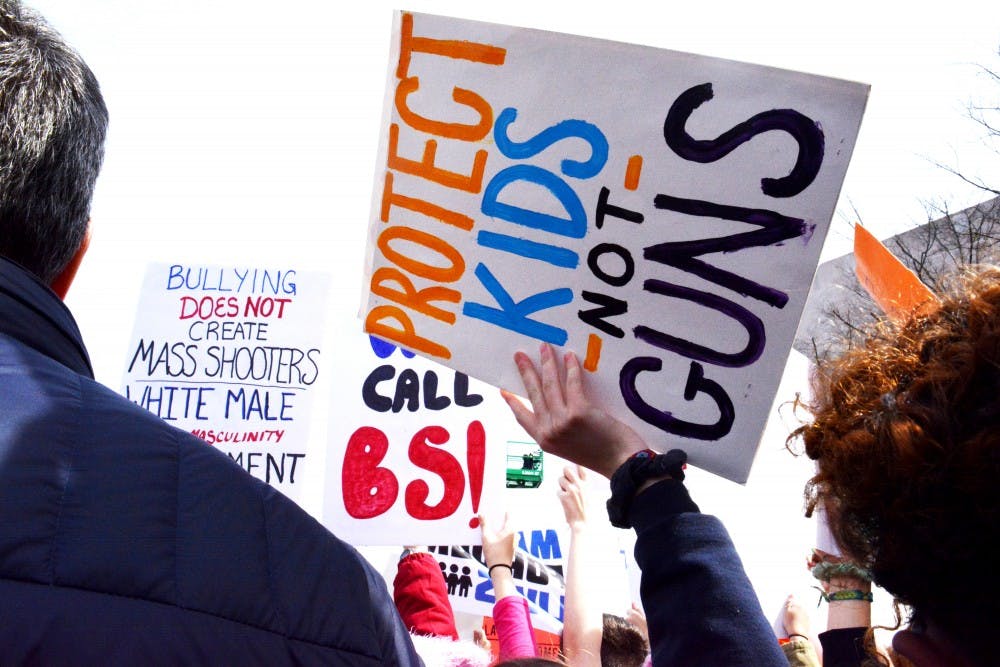周六，在华盛顿特区的“为我们的生命游行”集会上，一名学生抗议者在人群上方举着一个牌子。