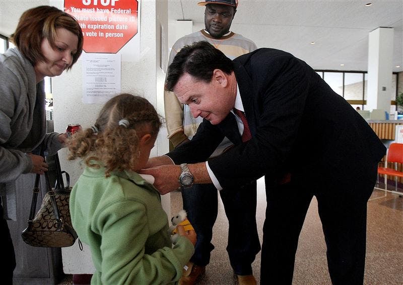 Indiana Secretary of State Todd Rokita gives his American Flag pin to Isis Breathitt, 5, of South Bend, Ind., after her parents, Joe and Sunshine Breathitt, took advantage of early voting in Indiana on Monday at the County-City Building in downtown South Bend. Sunshine, 30, voted for the first time.