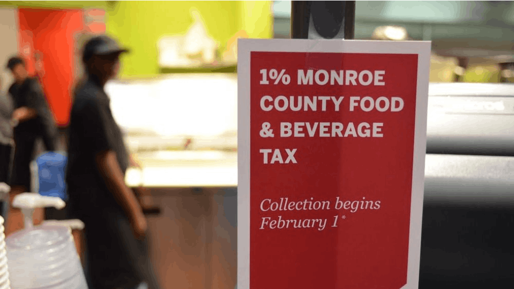 A sign hangs on the cash register of The Round café in Forest Residence Center informs students of the new Monroe County food and beverage tax. The 1-percent tax will not apply to food courts or stores on the IU campus for current students.