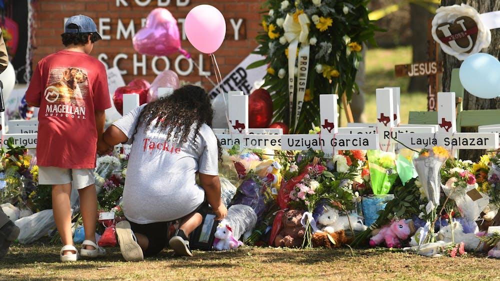 Family members place a picture at a memorial outside Robb Elementary School in Uvalde, Texas, where 19 students and two teachers died when a gunman opened fire in a classroom. 