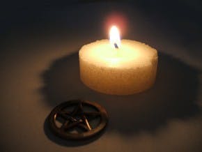 Sophomore Amy Payne lights a white candle on her altar to the deities she worships. The five points on the pentacle represent the elements earth, wind, fire, water and spirit.  COURTESY PHOTO