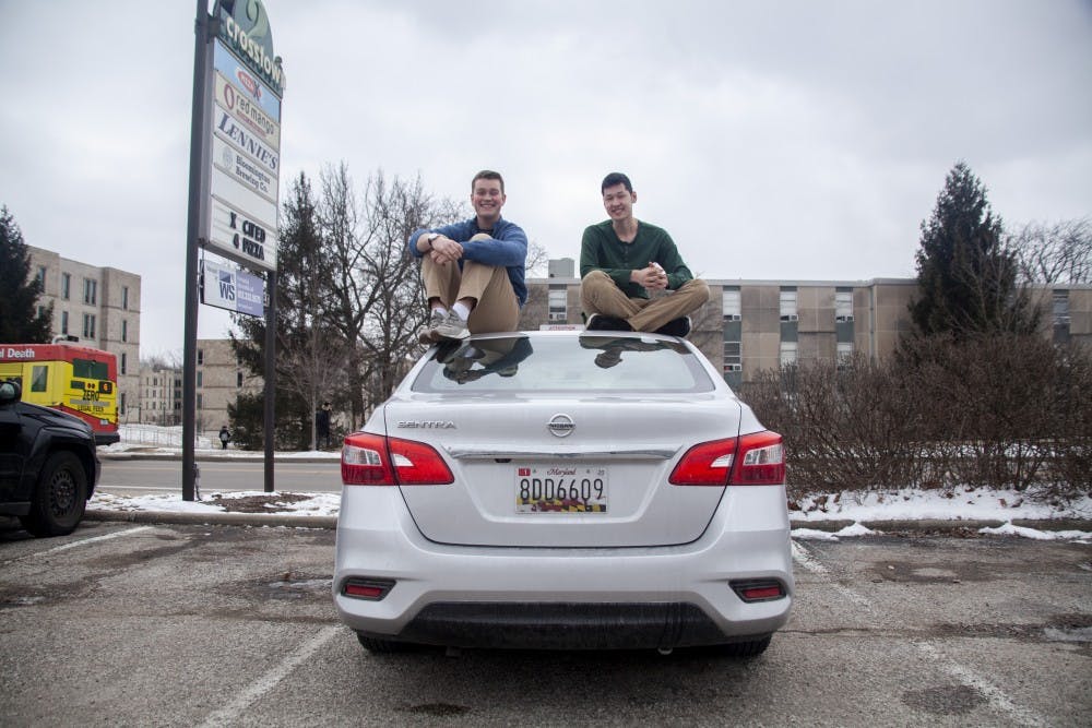 <p>Former IU classmates Michael McHugh and Daniel Jones sit on top of a car March 5 on 10th Street. McHugh and Jones started their own company, Nomad Rides, which hires student drivers to give rides to other students. </p>