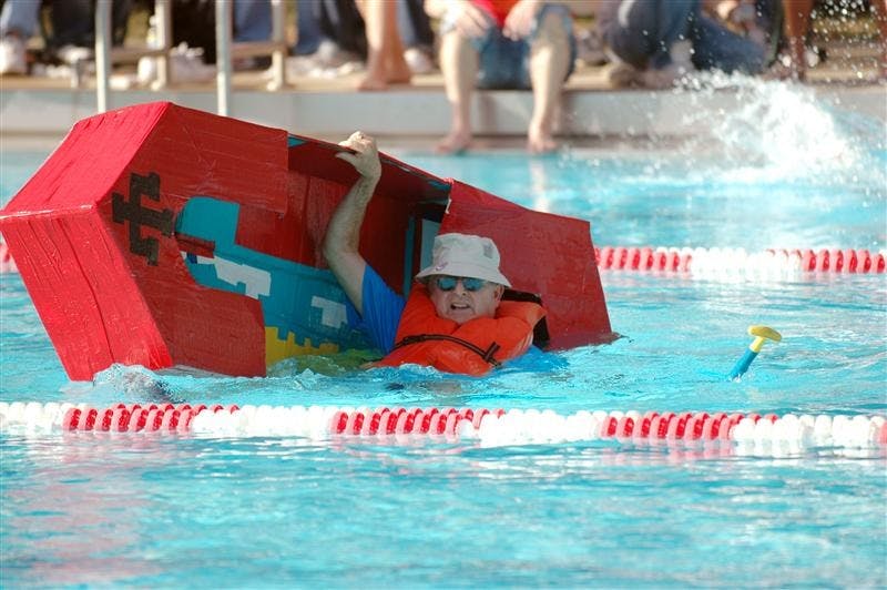 Dean McKaig holds on to the last moment after his boat capsized in the Cardboard Regatta on Friday at the Outdoor Pool. The 8th annual regatta featured the dean's challenge race featuring Deans Dick McKaig, Bob Goodman and Stephen Watt.