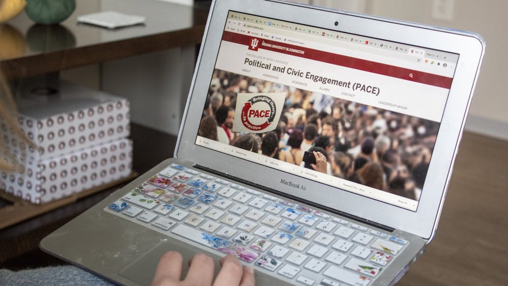 A student holds a computer displaying the Political and Civic Engagement website. 