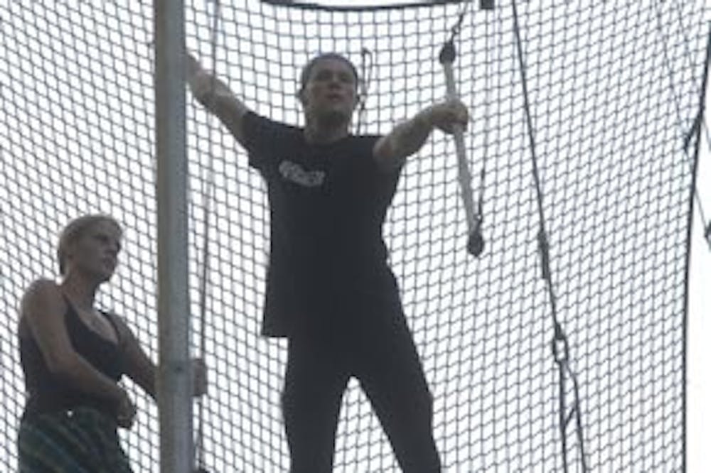 Chris Lemmon grabs onto the trapeze bar while team member Holly Faulk looks on.