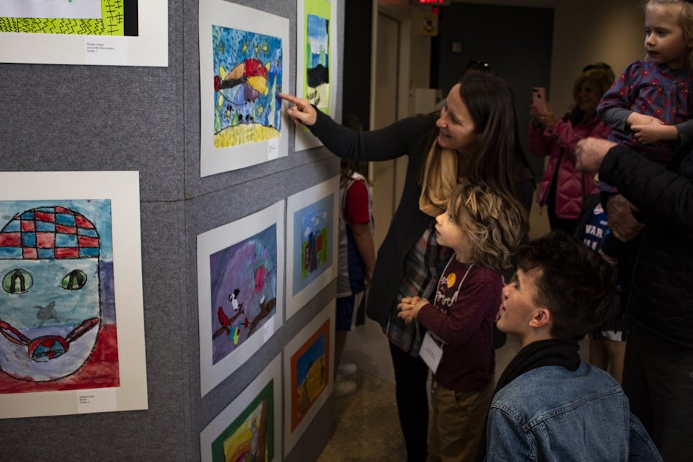 <p>Mother Sara Elgi points to kindergartener Julian Parks&#x27; artwork March 7 in the Sidney and Lois Eskenazi Museum of Art. Student artwork was showcased on the second floor of the in celebration of Youth Art Month.museum . </p>