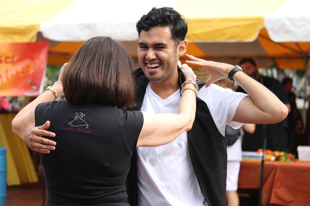 Gabriel Escobedo dances with Barbara Leininger, owner of the Arthur Murray Dance Studio, during a salsa dancing demonstration at the Bloomington Farmer's Market on Saturday. 