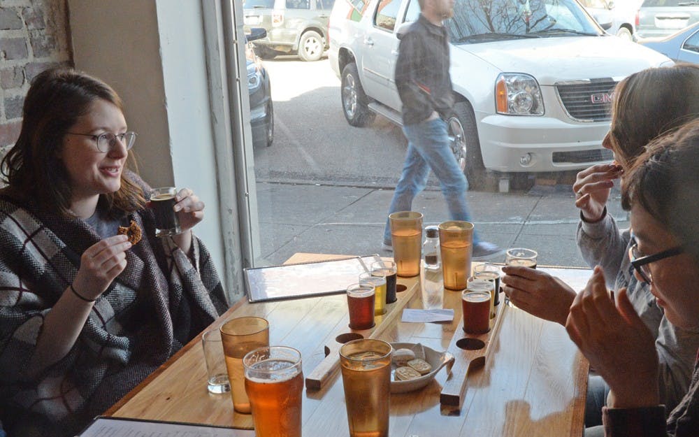 Amelia Lewis, 25, tries a Girl Scout cookie with a glass of beer at Function Brewing. She participated in the brewery's Girl Scout Cookies and Beer event Sunday.