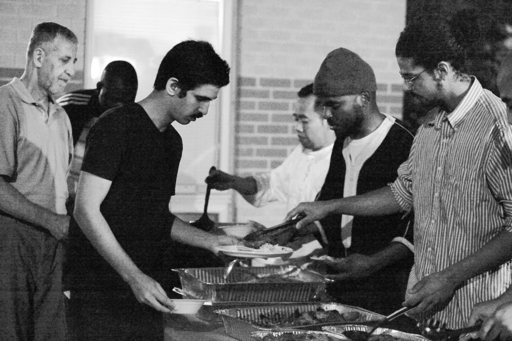 Hasan Ahmad serves food to other men after nightfall while celebrating Ramadan at the Islamic Center of Bloomington on Friday.  Even though they eat separately, dozens of men and women arrive at the ICOB every night to break their daylong fast.