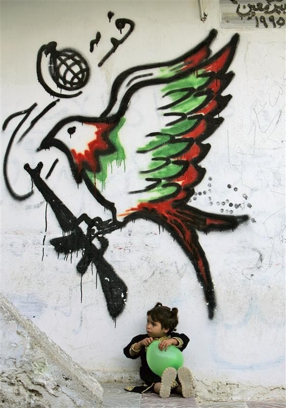A Palestinian girl plays with a balloon in front of a mural supporting Fatah, the ruling Palestinian political party, on Tuesday in the West Bank refugee camp of Kalandia, near Ramallah.