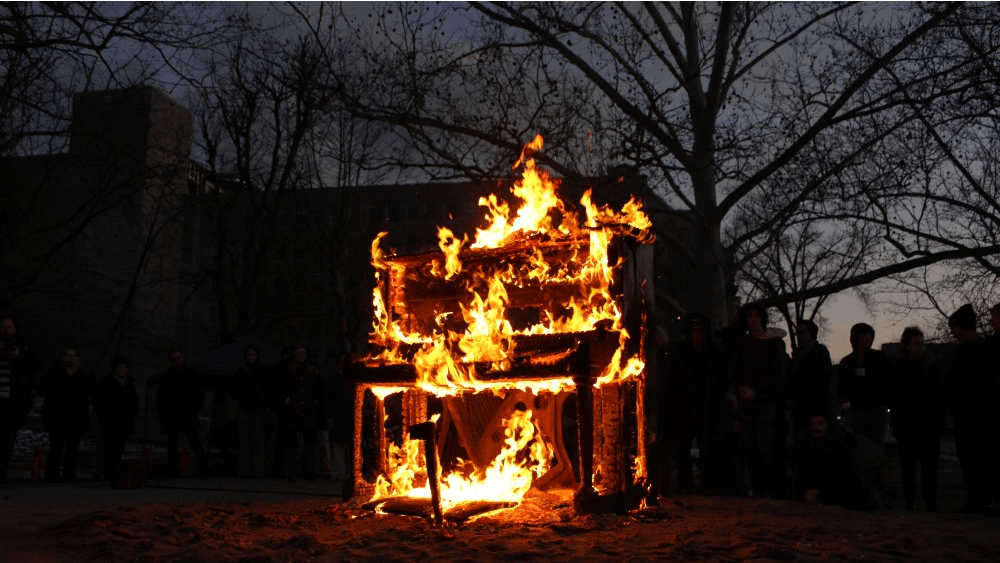 A piano burns on Wednesday evening in Dunn Meadow as an artistic demonstration by composer and artist Annea Lockwood. This performance is part of the Wounded Galaxies festival.&nbsp;