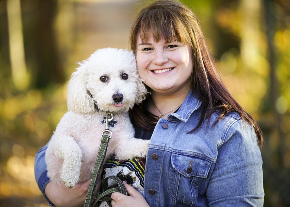 <p>Junior Sydney Ziegler plays with her dog Gilmour Sunday evening outside of the Fine Arts Plaza. Ziegler adopted the bichon frise poodle mix last November from the Bartholomew County Humane Society in Columbus, Indiana.</p>