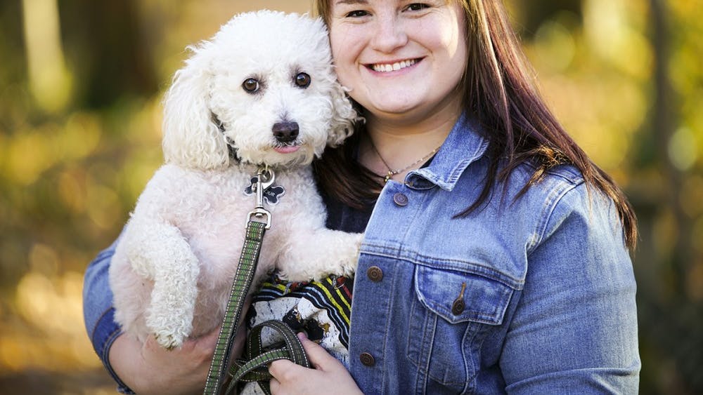 Junior Sydney Ziegler plays with her dog Gilmour Sunday evening outside of the Fine Arts Plaza. Ziegler adopted the bichon frise poodle mix last November from the Bartholomew County Humane Society in Columbus, Indiana.