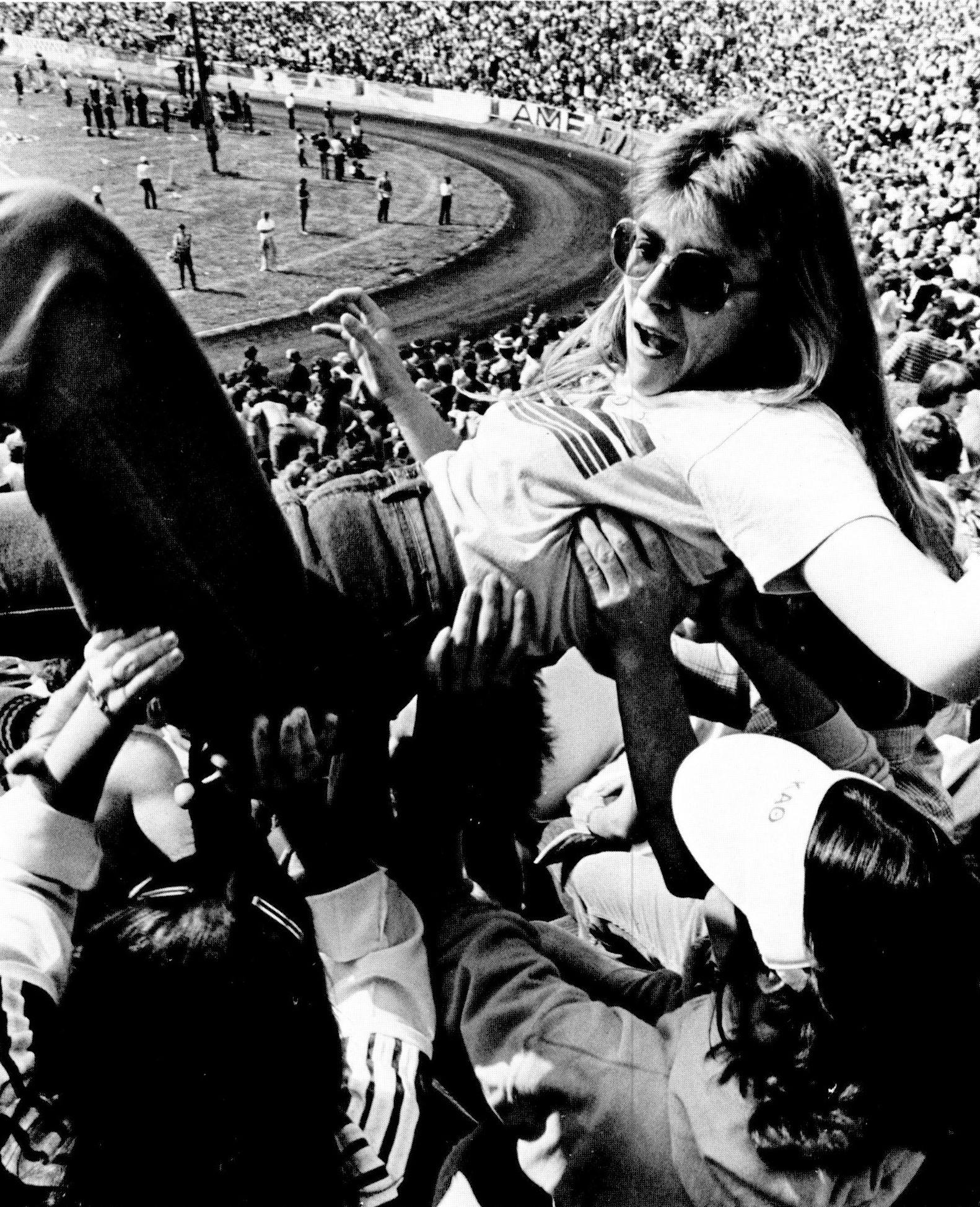 A specator is passed up to the top of the stands during the 1980 Little 500 race.