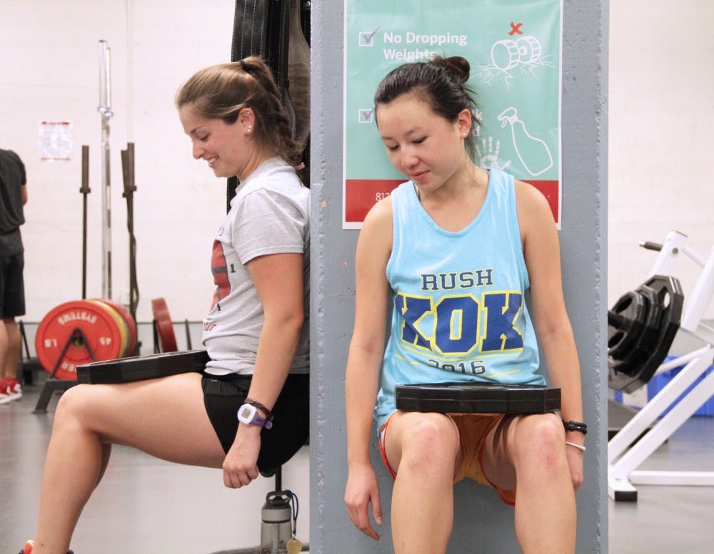 Sandy Lam (right) mentors Grace Boyd wall-sitting during their She’s the First charity workout Friday.
