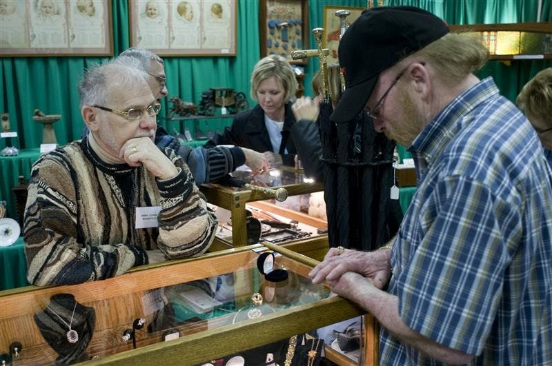 Dannie Chandler of Paul Fischer Antiques, looks on as Bloomington resident Ronal Hert tries on a ring during the 48th annual Kappa Alpha Theta Antiques and Decorative Arts Show Saturday afternoon at the Bloomington Convention Center. Proceeds from the sales benefit several different charities, including CASA. 