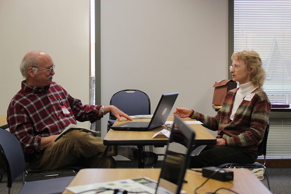 Senior navigator and Affordable Care Act assistance volunteer Tom Gruenenfelder discusses new features of his program's services with fellow volunteer Martha Dogan.  Employees like Gruenenfelder and Dogan help people in the Monroe County area sign up for health care under the Affordable Care Act.  