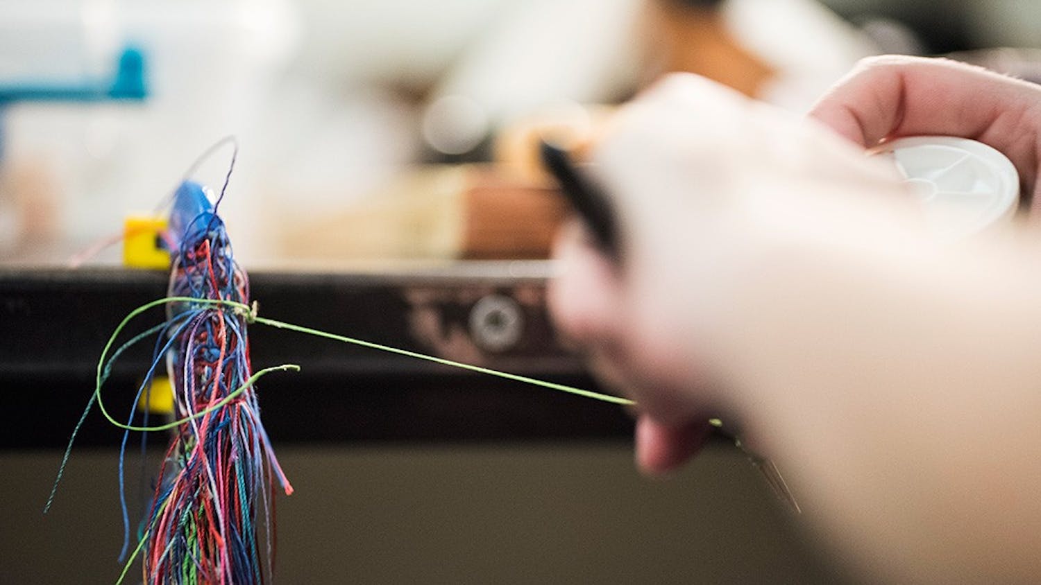 Sophomore Libby Ryan wraps green thread around her reed. The thread binds the two pieces of reed together. 