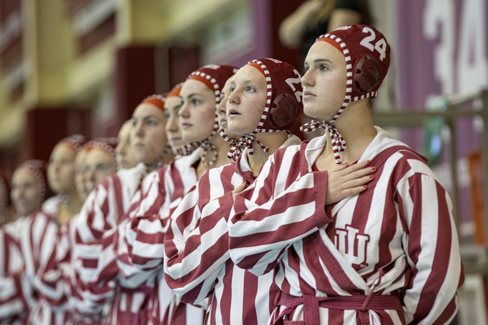 <p>Freshman driver Grace Hathaway and the Indiana water polo team stand for the National Anthem on March 26, 2022, at the Counsilman Billingsley Aquatic Center. Indiana won both of its final two home games of the season on senior day Saturday.</p>