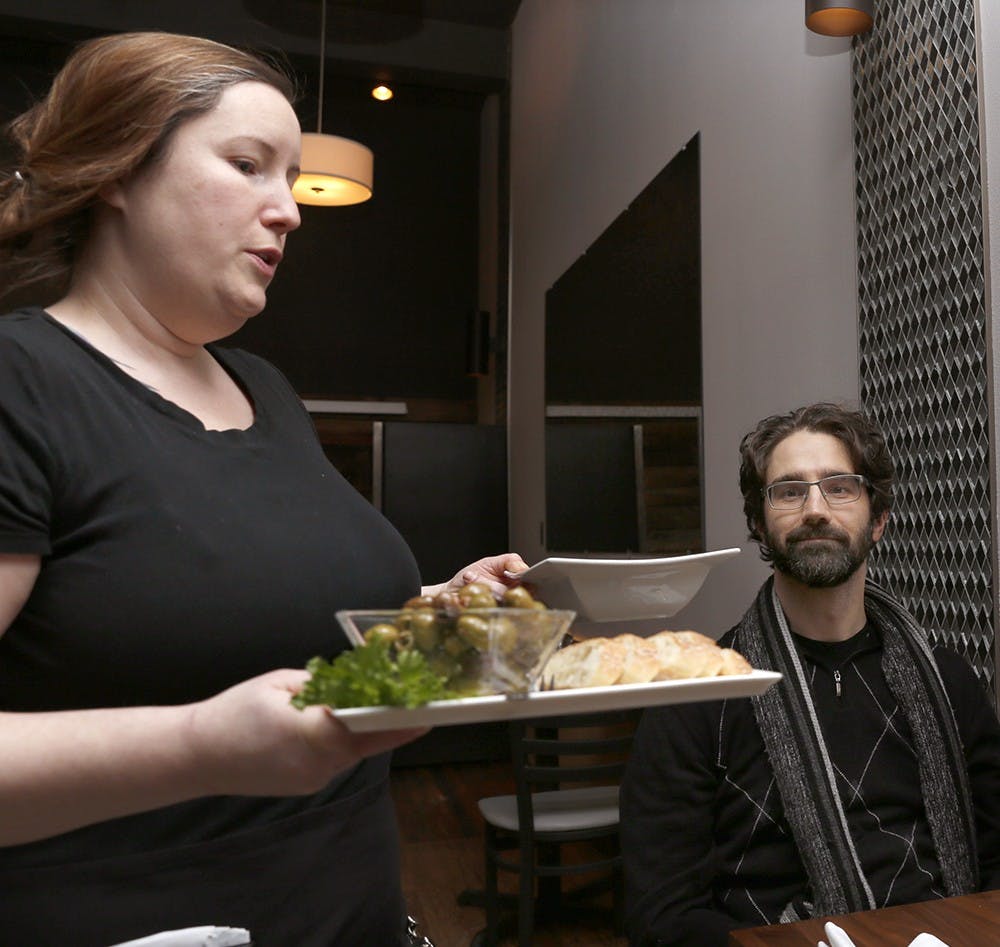 Alison May, left, serves a soup and olives as appetizers to Vini Frizzo Wednesday at NOCO . The restaurant was recently moved to North College Aveon the Square on Dec. 2015.  
