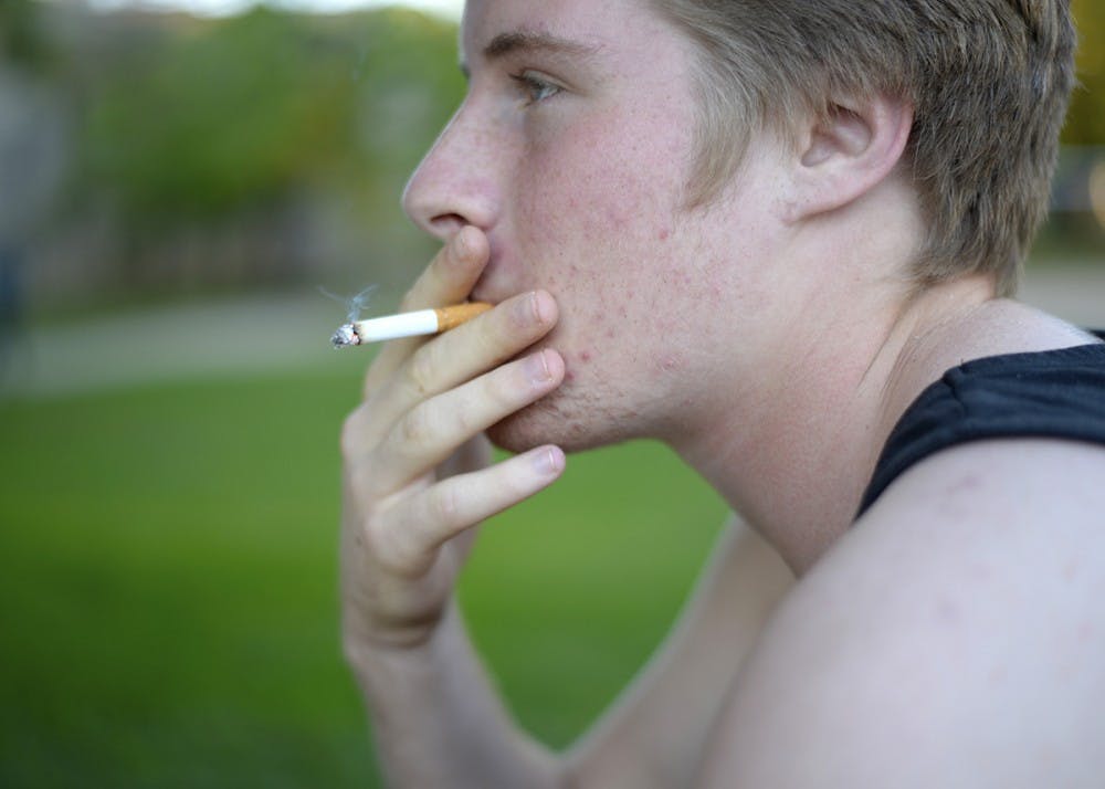 <p>Then-freshman James Freeborn smokes a cigarette near the smokers' table outside of Wright Quadrangle in 2014. The Indiana Chamber of Commerce wants to raise Indiana’s smoking age from 18 to 21 in 2018.</p>