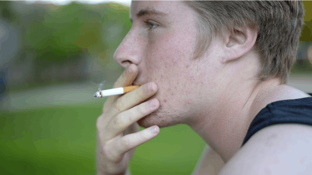 Then-freshman James Freeborn smokes a cigarette near the smokers' table outside of Wright Quadrangle in 2014. The Indiana Chamber of Commerce wants to raise Indiana’s smoking age from 18 to 21 in 2018.