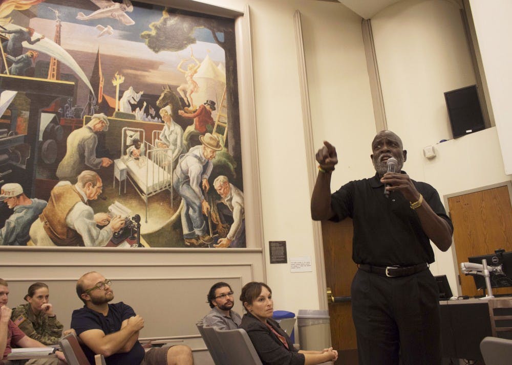 Charles Nelms, the first audience member to speak once the discussion opened up to the everyone, argues that the Benton murals, which have been split into many pieces across campus, need to be brought back together so the message of the entire piece of art is clear. The Benton mural, seen behind Nelms, portrays a hooded Klan member and has caused much controversy since it was created in 1941.