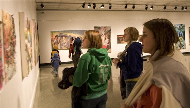 From left to right: seniors Abby Haler, Allyson Kennard, and Bree Haler, observe the BFA painting, "All the Good Ideas are Gone" by Annalea Van Nes, during the BFA Painting and Overseas Study Exhibitions at the SoFA Gallery on Friday.