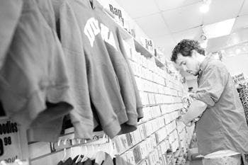 Store employee Brett Hayden stocks inventory Wednesday afternoon inside Tracks Music & Videos at 415 E. Kirkwood Ave. Hayden said the store began selling clothing in addition to music in an effort to keep the store afloat in a time of declining CD sales.