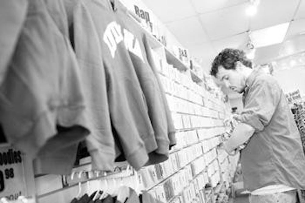 Store employee Brett Hayden stocks inventory Wednesday afternoon inside Tracks Music & Videos at 415 E. Kirkwood Ave. Hayden said the store began selling clothing in addition to music in an effort to keep the store afloat in a time of declining CD sales.
