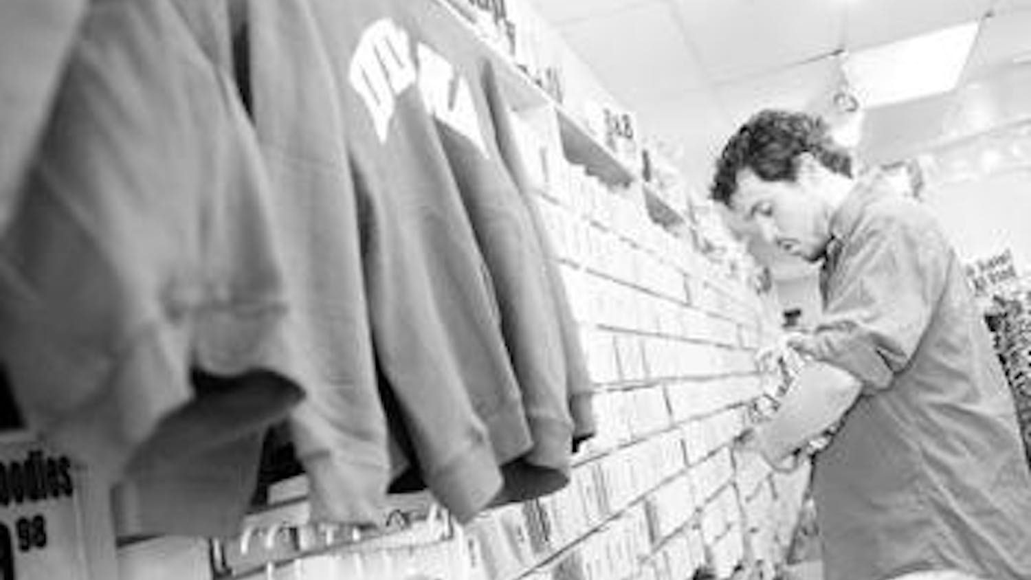Store employee Brett Hayden stocks inventory Wednesday afternoon inside Tracks Music & Videos at 415 E. Kirkwood Ave. Hayden said the store began selling clothing in addition to music in an effort to keep the store afloat in a time of declining CD sales.