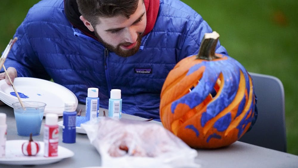 Freshman Tanner Graves decorates pumpkins while chatting with friends during Central’s Creepy Carnival Saturday evening outside of Teter Quadrangle. The event featured laser tag, free food catered by Residential Programs and Services Dining and an outdoor movie screening of the 1984 film Ghostbusters.