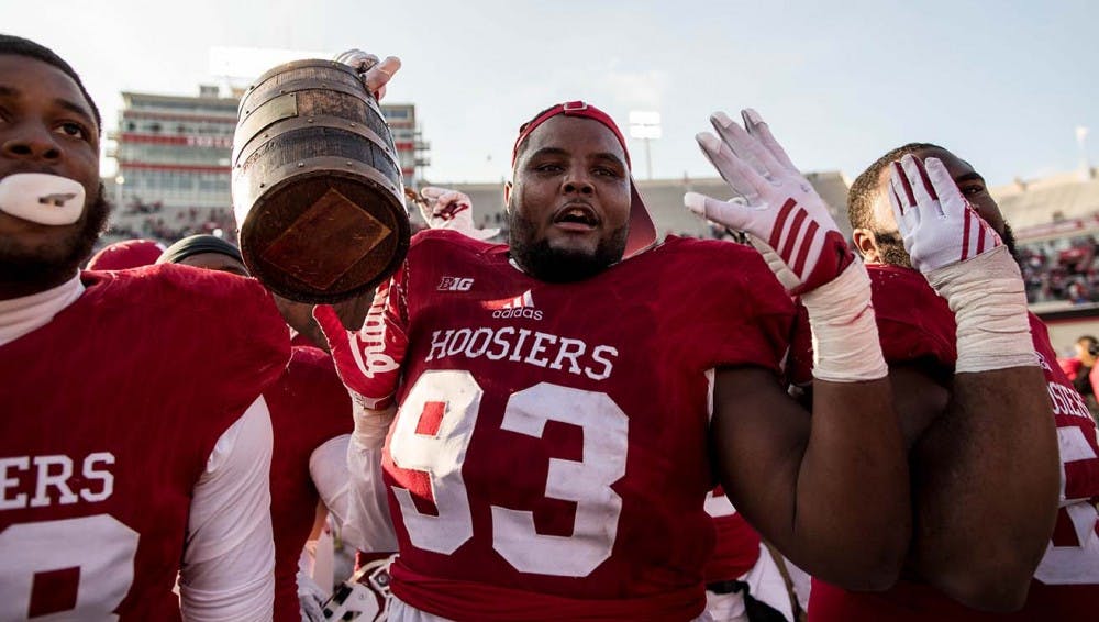 Senior defensive lineman Ralph Green III holds up the Old Oaken Bucket and four fingers after IU beat Purdue 26-24 for the fourth year in a row to keep the Old Oaken Bucket.