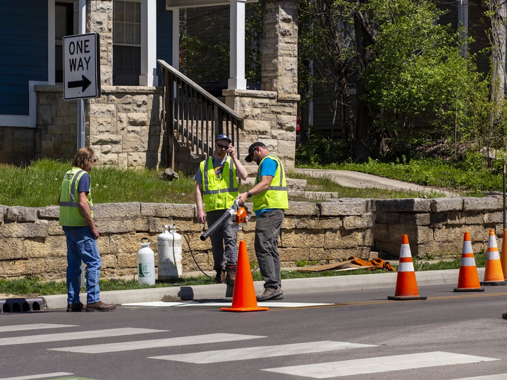 Workers blow off a freshly painted area April 12, 2023,at the intersection of East Seventh Street and North Dunn Street. The junction will now be an all way stop.