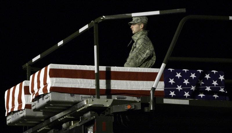 A member of a carry team at Dover Air Force Base, Del., stands with the transfer case containing the remains of Private Second Class Bryce E. Gautier, 22, of Cypress, Calif. and Cpl. Jason G. Pautsch, 20, of Davenport, Iowa, as they are lowered to the tarmac on Sunday.  Gautier, and Pautsch died with three other soldiers April 10, 2009, when their military vehicle was struck by a suicide vehicle-borne improvised explosive device in Mosul, Iraq.  