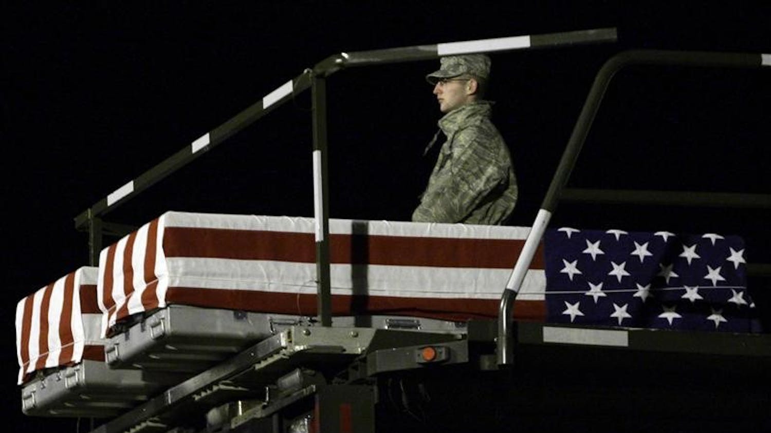 A member of a carry team at Dover Air Force Base, Del., stands with the transfer case containing the remains of Private Second Class Bryce E. Gautier, 22, of Cypress, Calif. and Cpl. Jason G. Pautsch, 20, of Davenport, Iowa, as they are lowered to the tarmac on Sunday.  Gautier, and Pautsch died with three other soldiers April 10, 2009, when their military vehicle was struck by a suicide vehicle-borne improvised explosive device in Mosul, Iraq.  