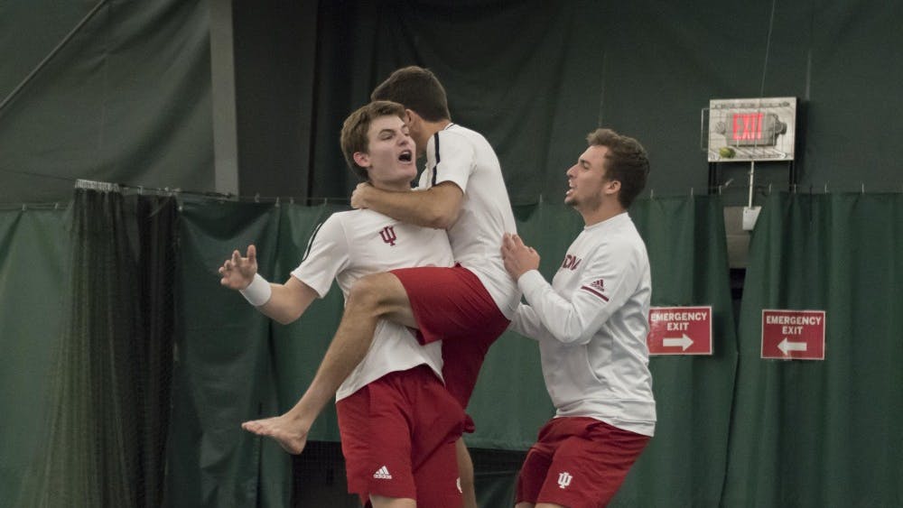 Freshman Andrew Redding is embraced by his teammates after his tough 6-2, 3-6, 7-6 (7-3) singles win over Wisconsin on Sunday at the Indiana University Tennis Center.&nbsp;