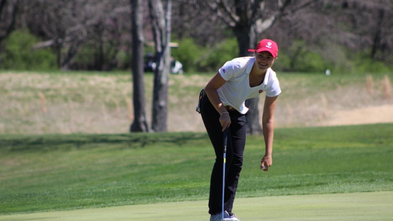Freshman Emma Fisher picks her ball out of the hole after sinking a putt on Saturday, April 8, 2017 during the IU Invitational at the IU Golf Course. Fisher won the 95th Women's State Amateur Championship at the Rock Hollow Golf Club in Peru, Ind on Friday with a score of +4.