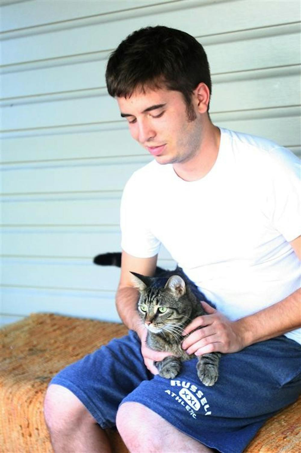 Senior Levi Shand holds a stray cat, Morris, that he got for his girlfriend as a Christmas present on Sept. 17 at his home.