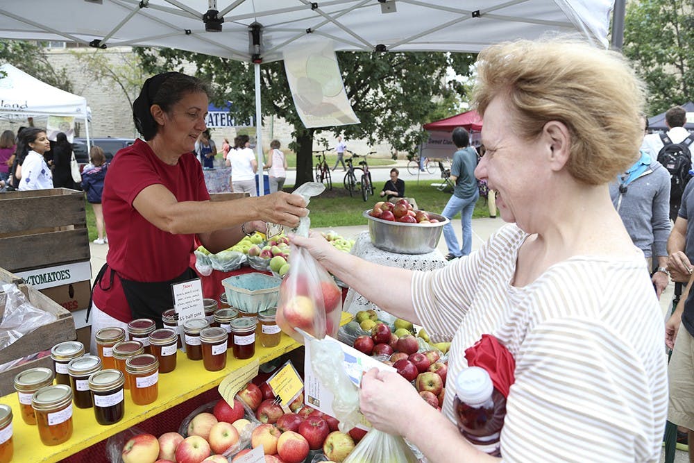 Local apple grower Janice Lehman sells apples to Wells librarian Kimberly Horne at the Big Red Eats Green festival on the IU Art Museum lawn on Wednesday afternoon. 