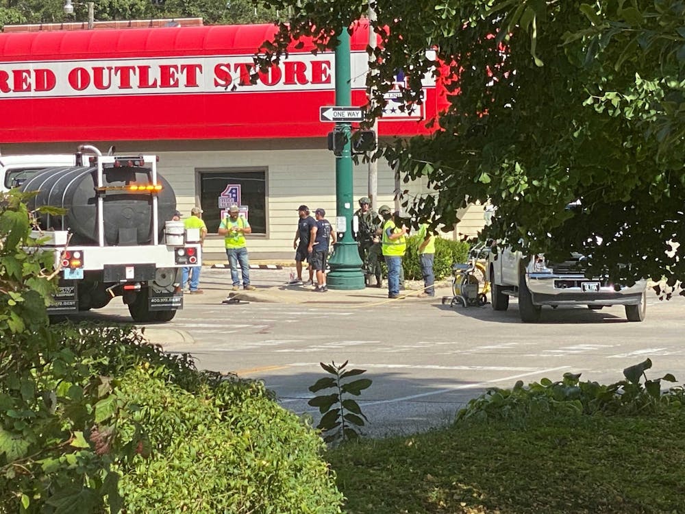Local police and other city workers gather near a manhole near West Second Street and South College Avenue around 3 p.m. Tuesday. They are responding to an ongoing situation involving an armed suspect hiding within the Bloomington sewer system.