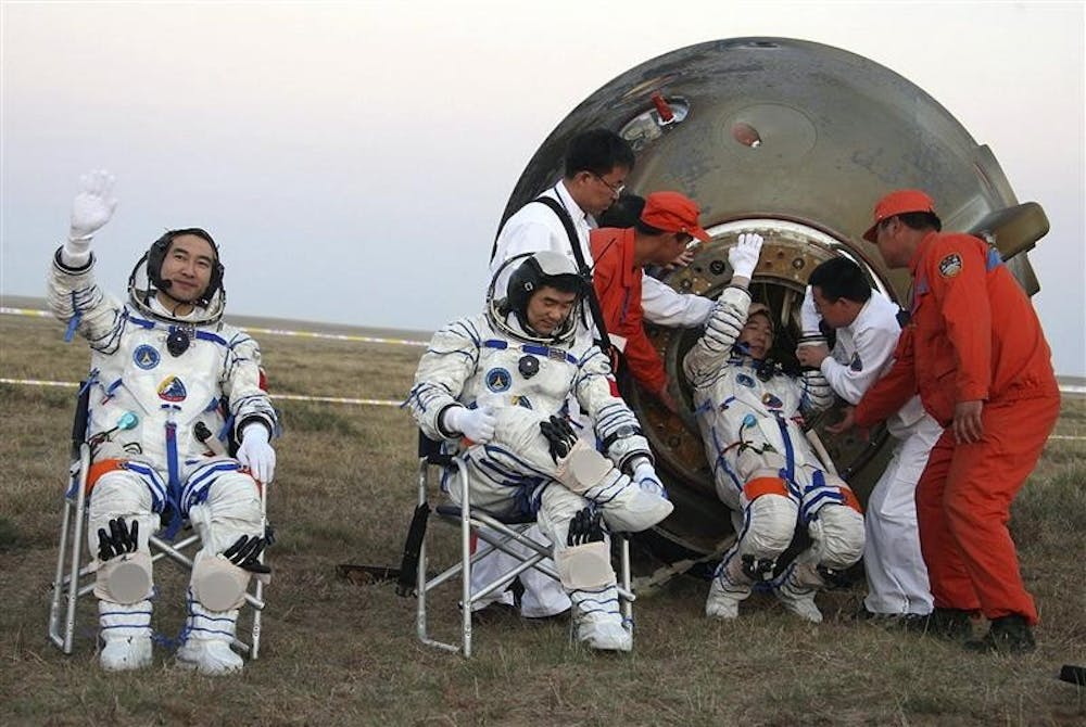 Chinese astronauts Zhai Zhigang, left waves near Liu Boming, center as Jing Haipeng is assisted out of the Shenzhou re-entry capsule after they landed on Sunday on the plains of China's northwestern Inner Mongolia Autonomous Region. Zhai conducted the country's first-ever spacewalk during the mission.