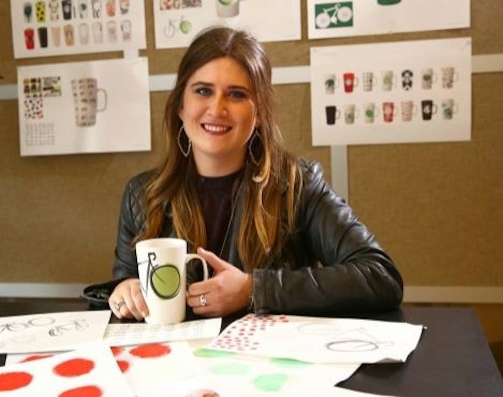 Alumna Suzie Reecer, senior designer of e-commerce for Starbucks, shows off the mug she designed. The bicycle design was partially inspired by Indiana University's Little 500 bicycle race.