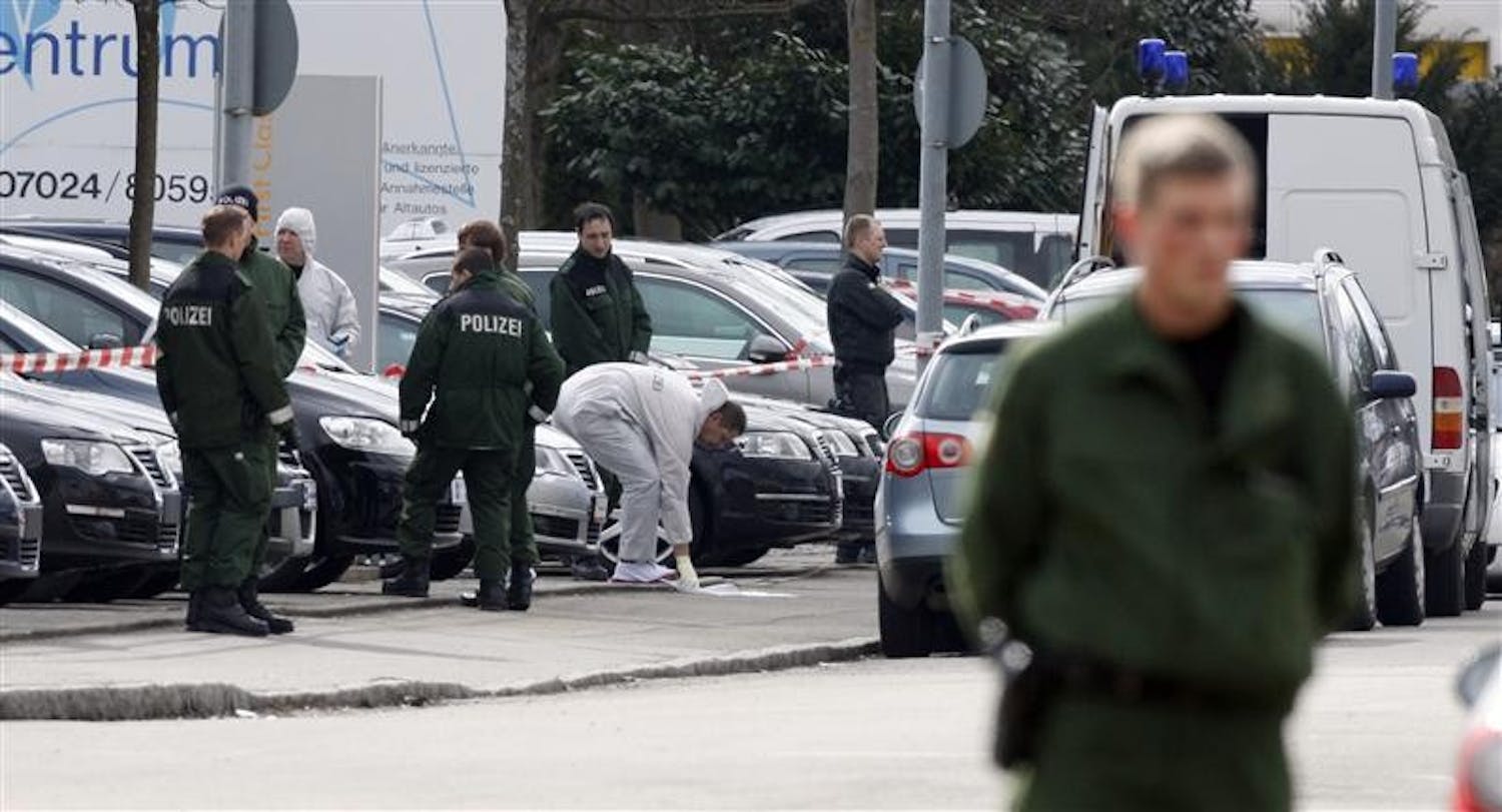 A police forensic expert works outside a car dealership, where a shooting incident took place Wednesday in Wendlingen, southern Germany. A 17-year-old gunman, dressed in black, opened fire at his former high school in southwestern Germany, killing at least 15 people before police shot him to death, state officials said. Nine students and three teachers were among the dead, State Interior Minister Heribert Rech said.