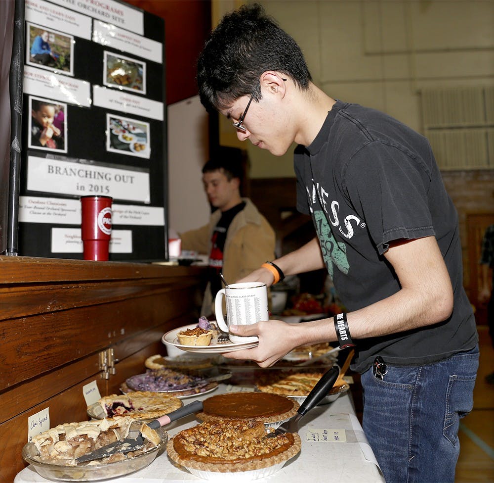 Joseph Burton grabs pies during "Hibernation Celebration" hosted by the Bloomington Community Orchard Sunday at Harmony School Gymnasium. The Bloomington Community Orchard is a non-profit organization to teach plant fruit trees in urban space. The event was opened to members of the organization to share opinions about future plans with pies and dinner. 