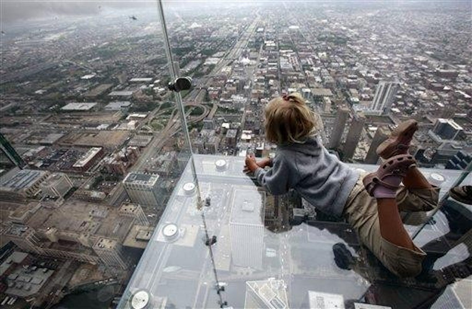 Anna Kane, 5, of Alton, Ill. looks down from "The Ledge," the new glass balconies suspended 1,353 feet (412 meters) in the air and jut out 4 feet (1.22 meters) from the Sears Tower's 103rd floor Skydeck Wednesday, July 1, 2009 in Chicago. The Ledge will open to public on Thursday.