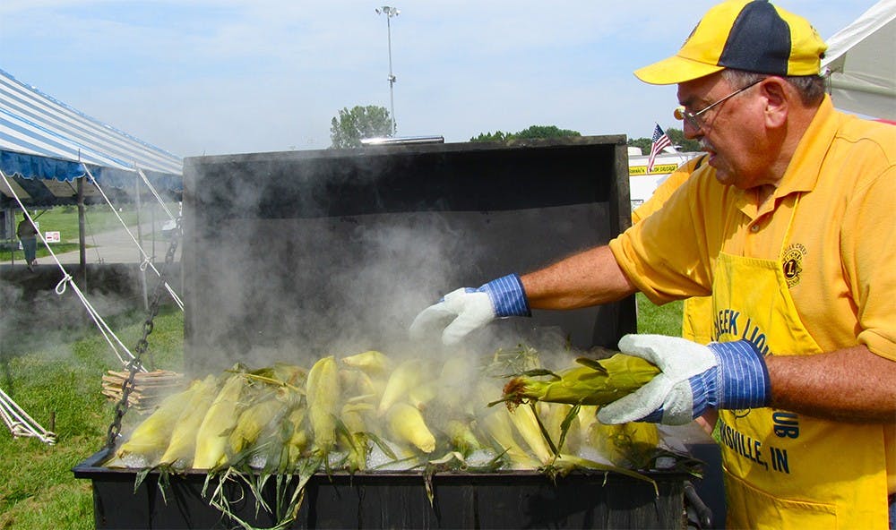 Roger Taylor takes ears of fresh corn off the grill at the Monroe County Fair. He guessed his booth sells around 60 dozen ears each day during the weekdays.